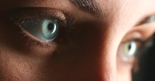 Sehen, Auge und Fokus mit einer Frau, die ihre Augen im Studio auf dunklem Hintergrund öffnet, Nahaufnahme