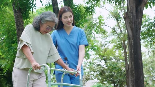 Asian woman caregiver assistance senior patient with walker for physical rehabilitation and therapy.