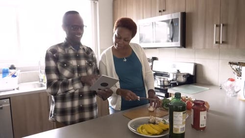 Adults Cooking Together in Kitchen, Using Tablet