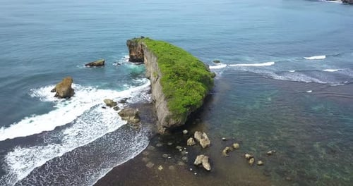 Drone shot of coral rock on the beach crashing by the wave with clear blue sea water