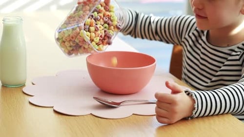 Child Preparing Colorful Cereal Breakfast at Table