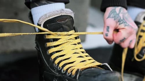 Person Tying Yellow Ice Skate Laces