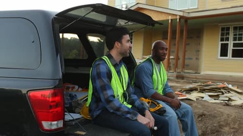 Construction Workers Sit Talking on Truck at Job Site