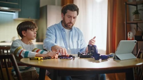 Father Son Assemble Car Sitting Home Kitchen Desk Closeup Serious Man Boy