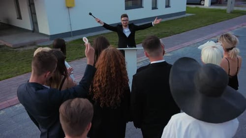 Auctioneer Holding a Gavel Presides over Real Estate Auction