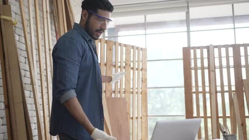Carpenter is working at woodshop.
