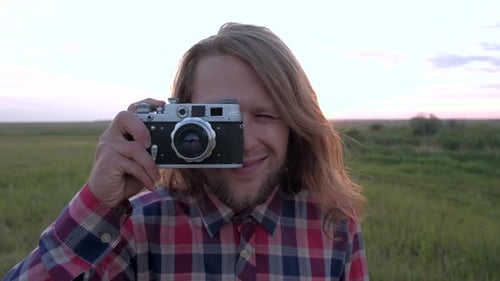 Man Smiling with Camera in Field at Sunset