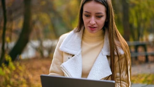 Woman Using Laptop in Autumn Park Setting