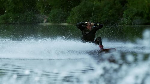 Wakeboarder führt Tricks in Zeitlupe aus und plätschert im sonnigen Urlaub durchs Wasser