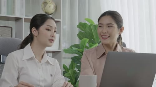 Two young enthusiastic businesswoman working together in the office workspace.