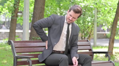 Man Sits on Bench with Back Pain