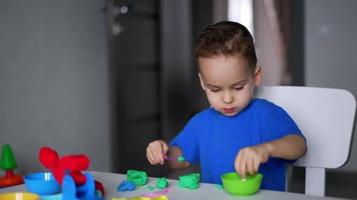 Young Boy Playing with Modeling Clay at Table