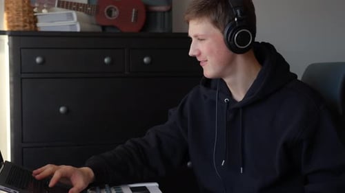 Teen Boy Composing Music with Headphones at Home