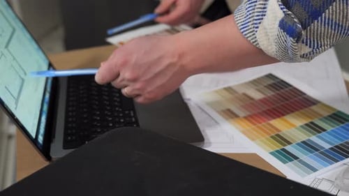 The Hands of Two Engineers Point to the Drawing with Their Pens