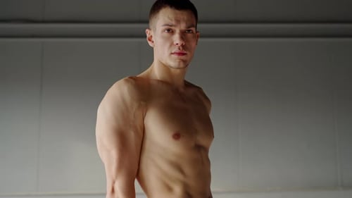 Fit Young Man Showing Off Muscles In Modern Gym Setting