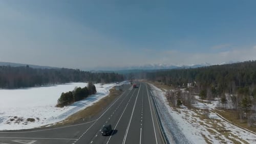 Luftaufnahme eines Lastwagens, der auf der Autobahn durch den verschneiten Wald in Burjatien, Russland