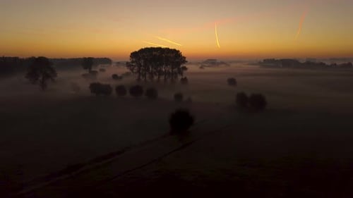 rising drone shot of the sunrise over fog farmland. Aerial view of the sun-up over misty fields in E