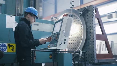 O operário da fábrica está programando uma fresadora CNC com um tablet.