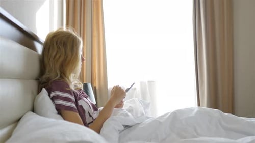 Woman Relaxing in Bed Using Smartphone