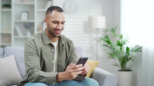 Man Using Smartphone on Couch in Modern Home