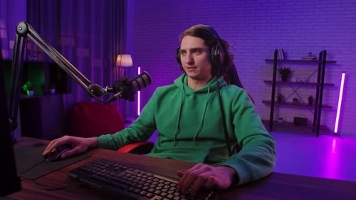 Man Puts on Headphones at Computer Desk