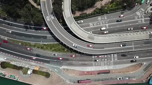 Aerial top view of vehicles on street and overpass in city, drone ascending over roads on sunny day