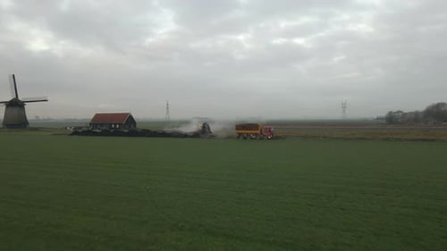 Aerial view of crane and truck that unloading mud in grassland