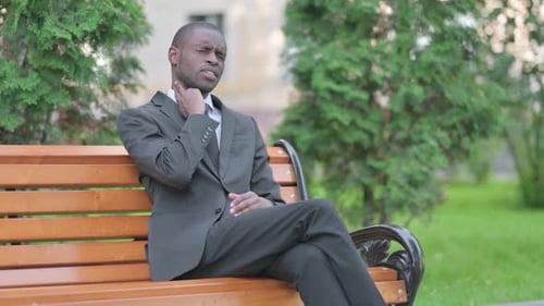 Man in Suit Massaging Stiff Neck on Park Bench