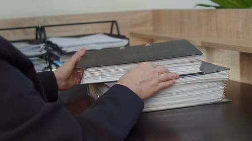 Businesswoman Arranging Document Folders on Office Desk