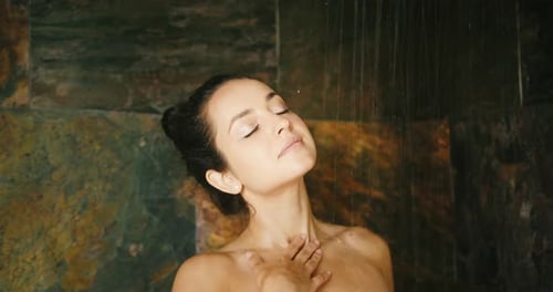 Woman Enjoys Shower in Natural Stone Bathroom