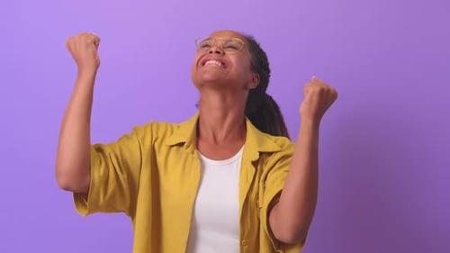 Junge erstaunte Afroamerikanerin tanzt vor Freude und macht Siegesgesten