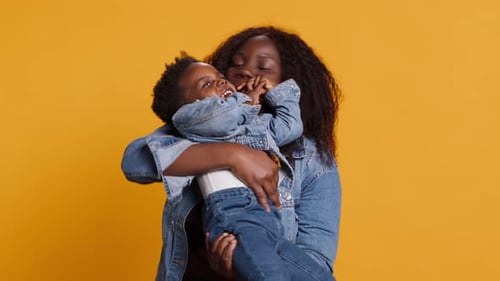 Smiling African American Mom Carrying Her Sweet Little Boy in Studio