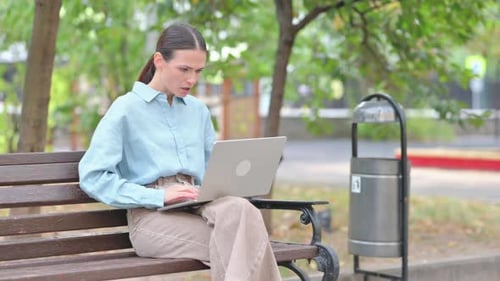 Woman Shocked by Loss on Laptop Outdoor
