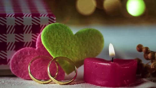Eheringe mit Herzmotiv und rotem Kerzenlicht zum Valentinstag