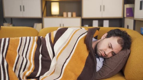 Man Lying on Couch Feeling Sick and Unwell