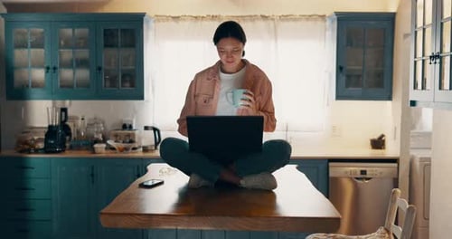 Woman Works on Laptop Sitting on Kitchen Table