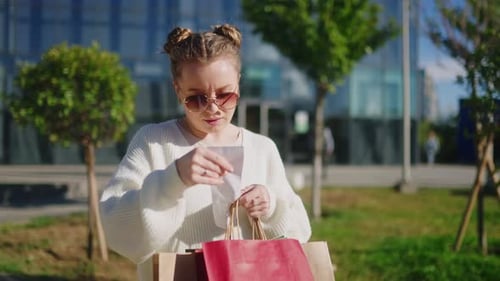 Woman Checks Receipt after Shopping Outside