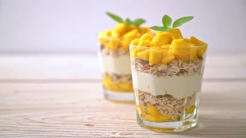 fresh mango yogurt with granola in glass - healthy food style