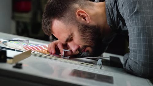 Worker in a Printing and Press Center Uses a Magnifying Glass and Check the Print Quality
