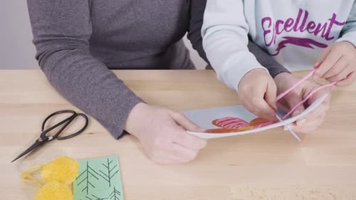 Little Girl Learning How to Sew with Her Mother at the Craft Table
