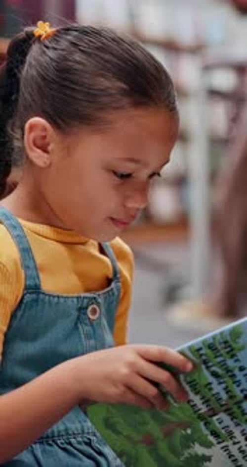 Happy, child and student with reading book in library for knowledge, fantasy story