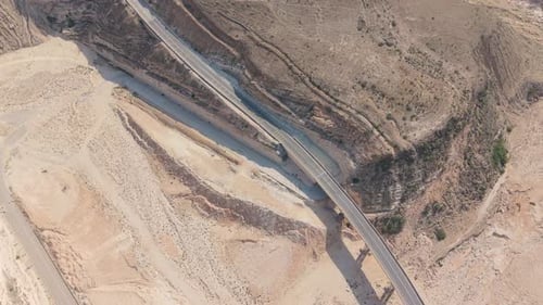 Aerial View of Winding Mountain Roads and a Concrete Bridge Spanning a Dry Riverbed Among Desert