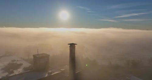 Aerial sunrise fog with tower wide shot during a sun glow