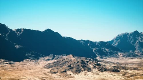Sweeping Drone View of Sunbathed Mountain Pass with Shadows and Textured Geology