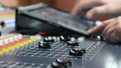 Hand adjusting audio levels on a colorful professional recording studio console