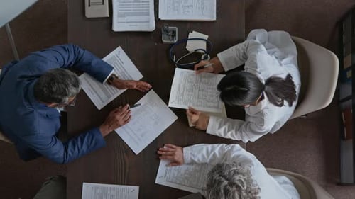 Male Medical Clinic Director Talking to Staff Doctors at Meeting