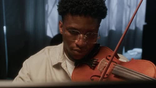 Young Adult Plays Violin with Focus Indoors