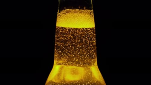 Close-Up Of The Top Of A Beer Bottle Where The Bubbles Rise
