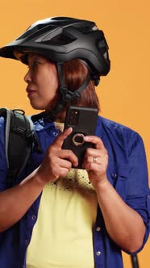 Woman Uses Smartphone Wearing Helmet and Backpack