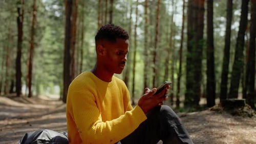 African American Man Using Smartphone in the Forest